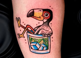 a cartoonish tattoo of a toucan taking a bath in a glass of some drink