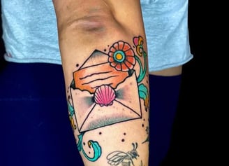 Traditional american tattoo of a love letter with a seashell and flowers
