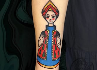 Tattoo of a russian doll but cartonish.