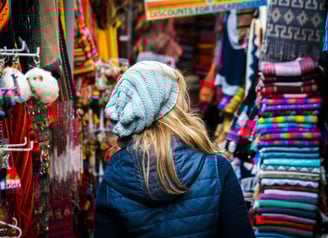 a woman in a blue jacket in a colorful market in Cusco Peru