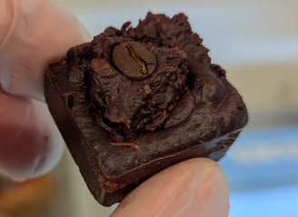 a person in gloves and gloves holding a piece of chocolate cake