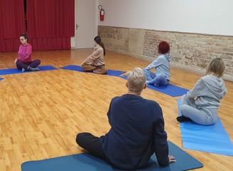 a group of people sitting on yoga mats in a circle, classe di esercizi di bioenergetica