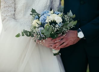 Des mariés en train de tenir le bouquet/a bride and groom holding a bouquet of flowers