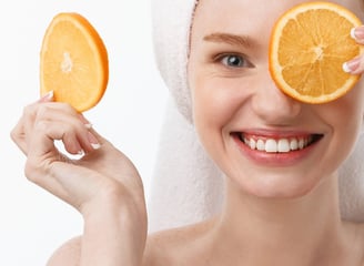 Vrouw met handdoek op haar hoofd en een appelsien voor haar ogen