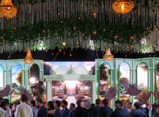 a group of people standing on a stage in front of wide led screen with garden scenery on it