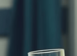 a woman in a green scrub talks to a patient. She is giving her a glass of water.