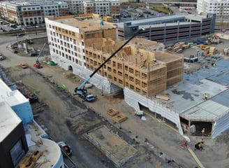 a large Wood Paneling Frame building with a crane in the foreground