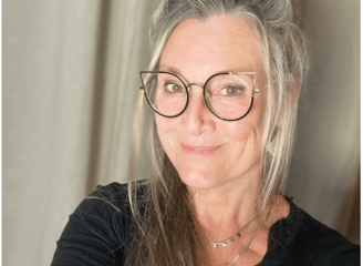 Une femme blonde Avec de grande lunette et un pull noir