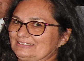 Une femme avec des cheveux brun des lunettes rouge avec un grand sourire 