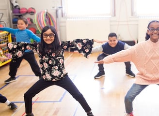 Elementary students to a squat exercise.