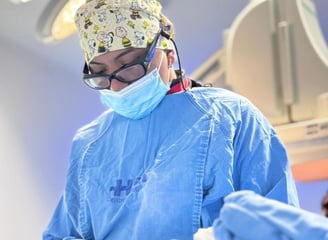 Una persona con una bata quirúrgica está realizando un procedimiento quirúrgico