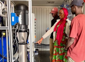 a man and woman standing in a container on a water plant