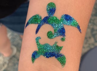 sea turtle glitter tattoo on skin with glitter colors of blue, aqua, and green