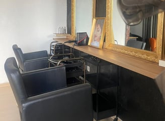 Vue intérieure du salon X Tension NC avec fauteuils professionnels et miroir doré, un espace dédié à