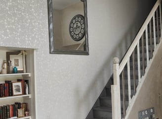 Miroir à cadre métal sur mur gris clair et escalier blanc