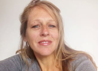 une femme blonde avec un pull gris