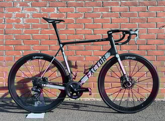 a custom Factor O2 parked on the side of a brick wall