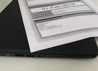 a laptop computer sitting on a desk with a paper document