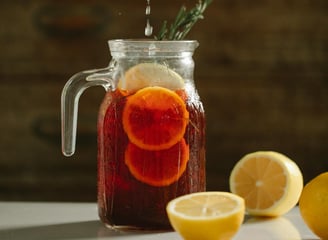 a person squeezing lemonade into a jar of lemonade
