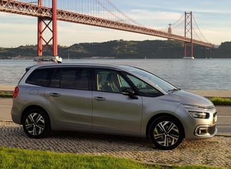 Imagem de um carro em primeiro plano, ao fundo, a Ponte 25 de abril, entre Lisboa e Almada