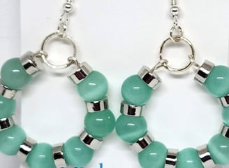 a pair of earrings with green beads and silver hoop earrings