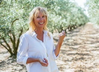 Femme blonde chemise blanche avec un sourire dans les oliviers
