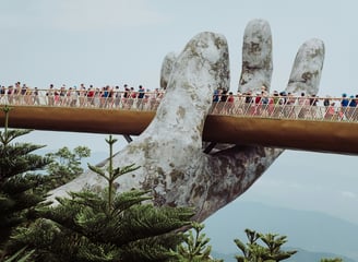 Golden Bridge in Vietnam held by giant stone hands, surrounded by misty hills and lush greenery.