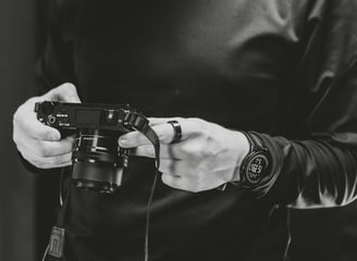 A man holding a camera in a podcast studio.