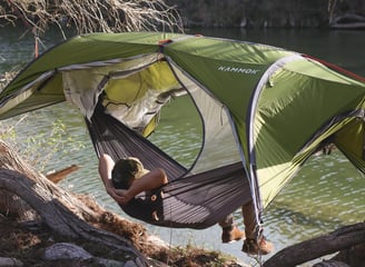 a person sitting in a hammock with a tent