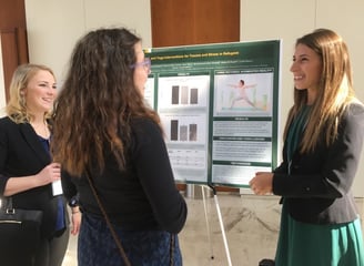 Dr. Grasser talks to two individuals about research on yoga, art, & dance interventions for families