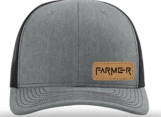 a gray and black hat with a leather patch on the front of a hat