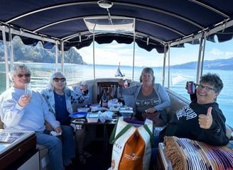 a group of people sitting on an eco-friendly all electric boat celebrating a birthday