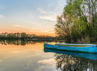 a blue boat on the water at sunset