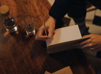 A picture of a man's hand preparing to sign the inside of a novel