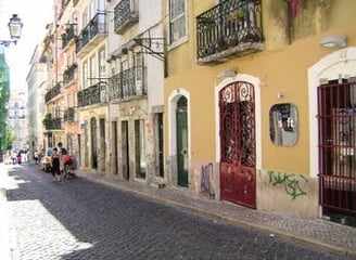 Lisbon - row of apartments & businesses with doors & false balconies facing the cobblestone street