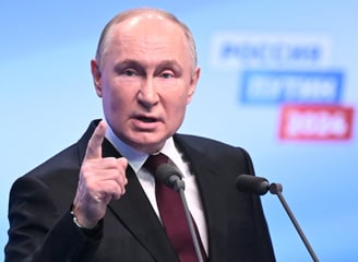 Vladimir Putin in a suit and tie is giving a speech