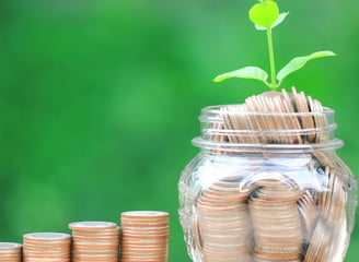 a jar of coins with a plant growing out of it