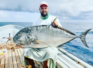 Angler holding a massive Giant Trevally on a Zanzibar fishing charter, perfect for deep-sea fishing 