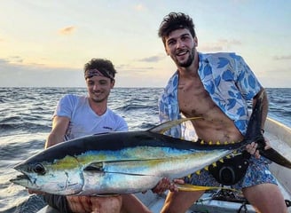 Two happy fishermen holding a large yellowfin tuna on a deep-sea fishing charter in Zanzibar