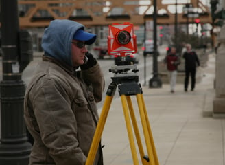 a man in a blue jacket and a camera on a tripod