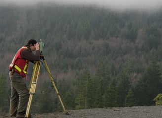 a man in a red vest and a yellow vest is holding a tripod