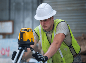 a man in a hard hat and safety vest holding a laser level