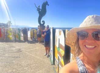 a woman in a hat and sunglasses is taking a selfie
