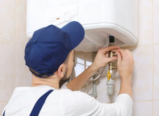 A plumber installing a water heater in a bathroom