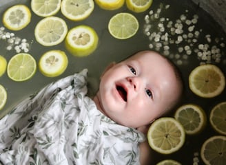 bain de lait bebe avec bebe entouré de citron et de fleurs ou d'autres fruits