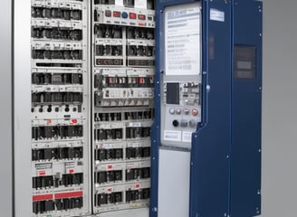 A gray industrial electronic device with multiple ports on the top and a black panel on the front labeled 'Mitsubishi' and 'FX3G-24M'. The unit has a rectangular shape with various connectors exposed, indicating its use for automation or control purposes.