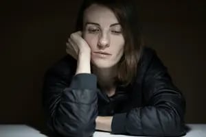 Mulher apoia na mesa com expressão triste