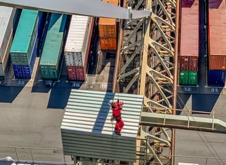 Ein Arbeiter seilt sich von einem Kran im Hafen ab.