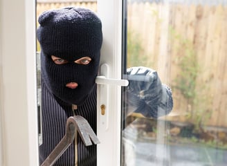 masked burgler breaking into home