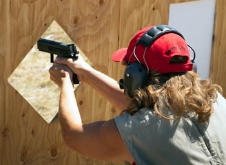 Female shooting 9mm handgun on range